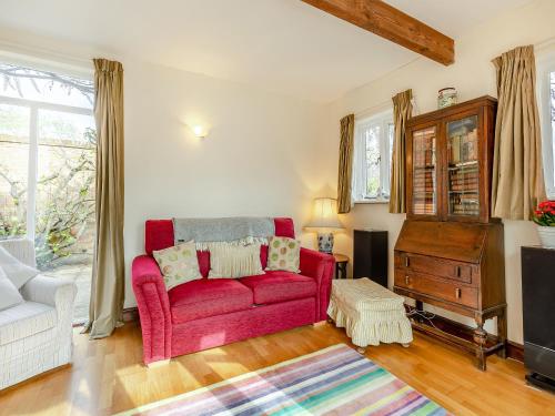 a living room with a red couch and a tv at The Coach House in Aldington