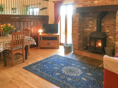 a living room with a fireplace and a table with a rug at The Coach House - 15661 in Tytherton Lucas