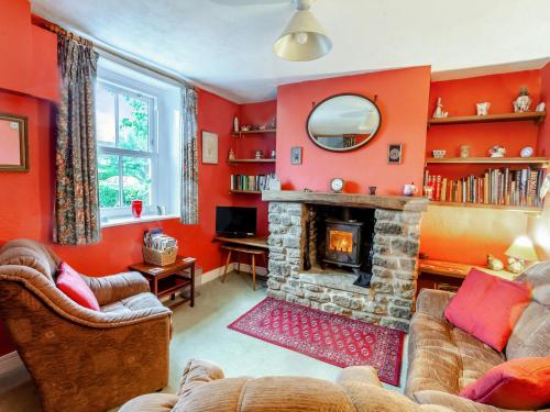 ein Wohnzimmer mit roten Wänden und einem Kamin in der Unterkunft Old Orchard Cottage in Dilton