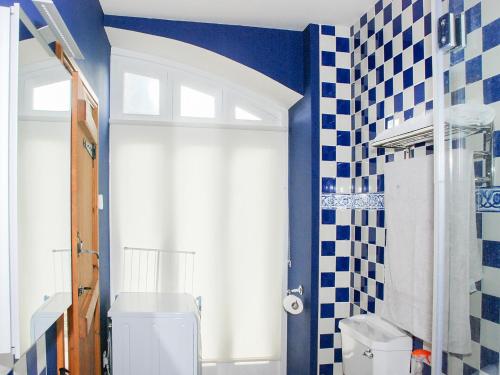 a bathroom with a toilet and blue and white tiles at The Byre in West Stour