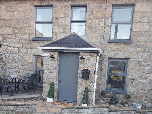 a stone building with a gray door and a table at Portland Cottage in Mousehole