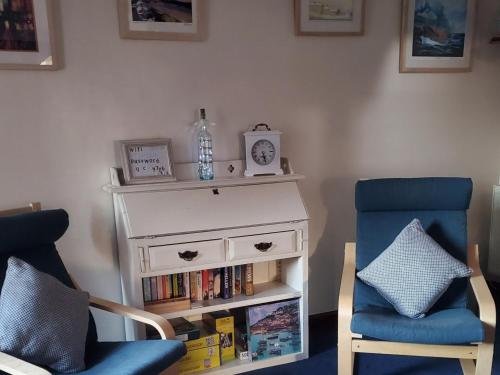 a room with a white dresser and a chair and a book shelf at Portland Cottage in Mousehole