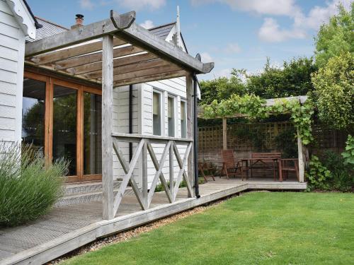 une pergola en bois sur une maison avec une terrasse dans l'établissement Mussel Cottage, à Middleton-on-Sea