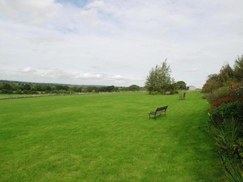 a park with two benches in a grassy field at Abbotts Ball Farm in Potterne
