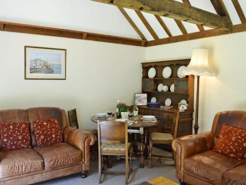 a living room with leather furniture and a table at Ivy Cottage in Sandhurst