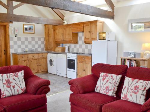 a kitchen with two red chairs and a white refrigerator at Shyre Stable - 18437 in Bempton