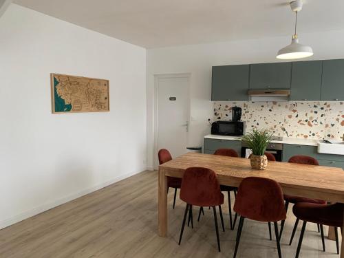 une cuisine et une salle à manger avec une table et des chaises en bois dans l'établissement Bretagne maison proche de la mer de 4 à 8 personnes, à Plouégat-Guérand