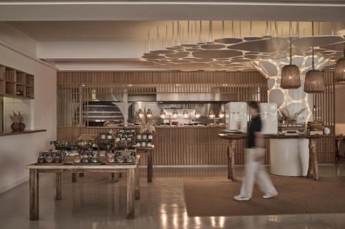 a person walking in a room with a kitchen at Nikki Beach Resort & Spa Porto Heli in Porto Heli