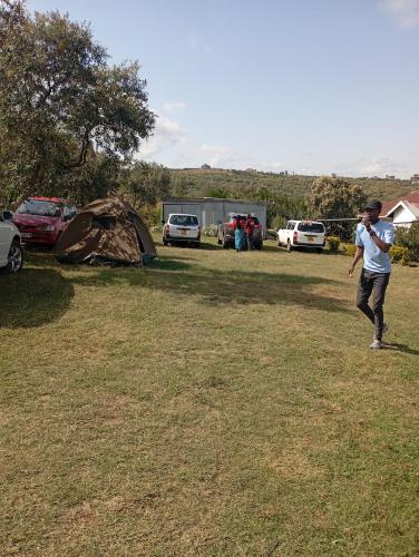 a man flying a kite in a field with a tent at Longonot View Camp and Accommodation, Naivasha in Naivasha