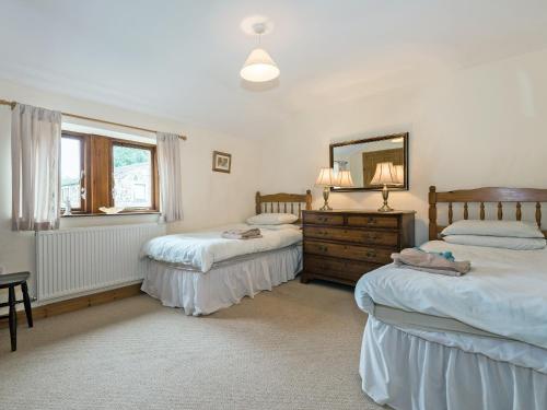 a bedroom with two beds and a mirror and a dresser at Dipper Fold in Hebden