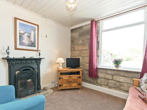 a living room with a fireplace and a television at Tinakori in Staithes