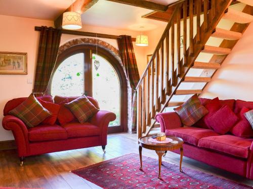 a living room with two red couches and a staircase at Acorn Barn in Foggathorpe