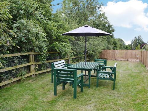 a picnic table with an umbrella in a yard at Acorn Barn in Foggathorpe