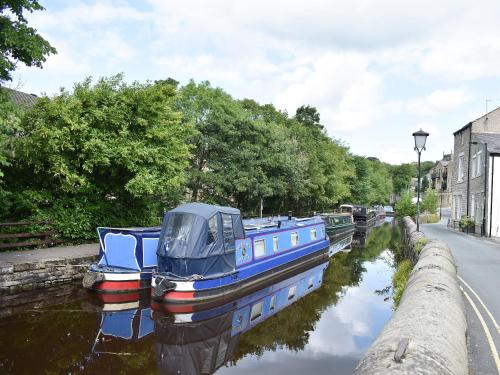 a blue boat is docked on a canal at Crown Hill Lodge in Cononley