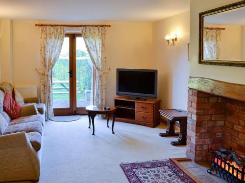 a living room with a tv and a fireplace at Carters Cottage in Puncknowle
