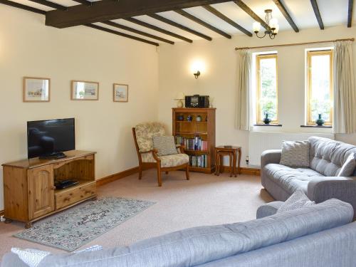 a living room with a couch and a flat screen tv at 2 Sawmill Cottages in Puncknowle