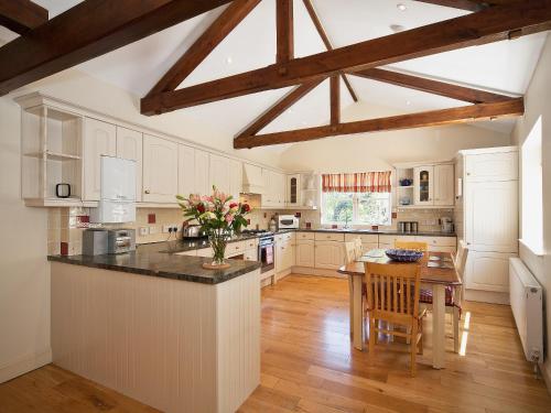 a kitchen with white cabinets and a wooden table at Ware House Cottage in Lyme Regis