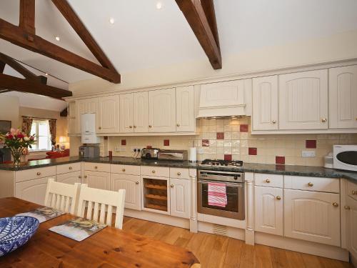 a kitchen with white cabinets and a wooden table at Ware House Cottage in Lyme Regis