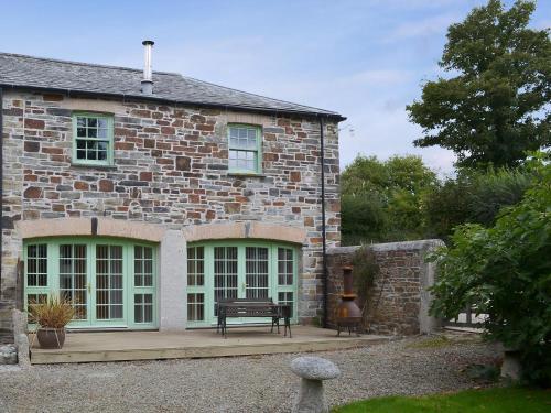 a stone house with a bench in front of it at The Coach House - 24439 in Bodmin