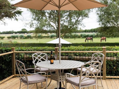 a table and chairs with an umbrella on a deck at 1 Luckington Stables-W8321 in Holcombe