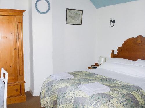 a white bedroom with a bed with a wooden headboard at Hollies Cottage in Draycott