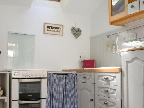 a kitchen with white cabinets and a stove top oven at Hollies Cottage in Draycott