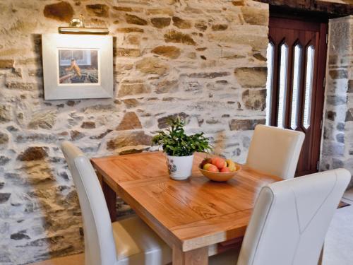 - une table en bois avec des chaises et une corbeille de fruits dans l'établissement Penno Cottage - 24440, à Bodmin