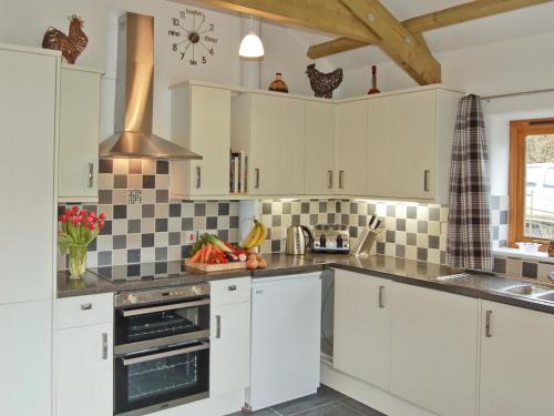 a kitchen with white cabinets and black and white tiles at The Stables in Bodmin