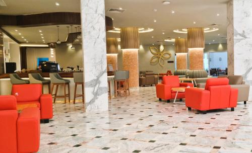 a lobby with red chairs and a bar at Sentido Marillia Resort & Spa in Hammamet