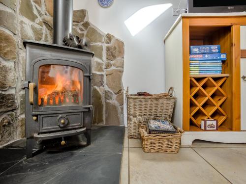 a fireplace in a room with a stone wall at Appletree Cottage in Kirkton of Tealing