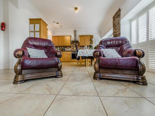 two leather chairs in a living room with a table at The Old Stables in Kirkton of Tealing