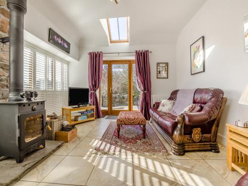 a living room with a leather couch and a fireplace at The Old Stables in Kirkton of Tealing