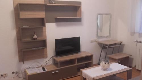 ein Wohnzimmer mit einem TV und einem Tisch in der Unterkunft Apartment Pavlešić in Slunj