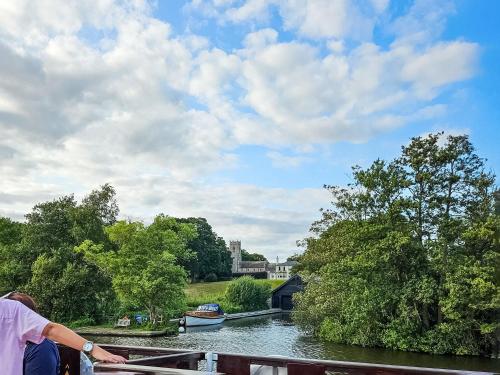 a man standing on a balcony looking out over a river at Elm Barn Lodge in Freethorpe