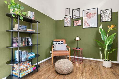 ein Zimmer mit grünen Wänden und einem Stuhl und Bücherregalen in der Unterkunft LIGHTHOUSE - Perfekt für Gruppen - 2 Whg - Zentral - PS5 & Switch in Rotenburg an der Fulda