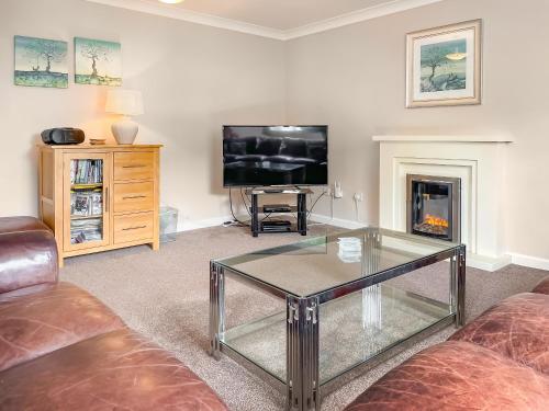 a living room with a glass coffee table and a tv at Beach Retreat - E5558 in Mundesley