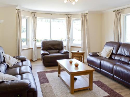 ein Wohnzimmer mit Ledersofas und einem Couchtisch in der Unterkunft March Cottage in Glenrossal