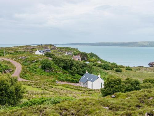 a white house on a hill next to the ocean at Tigh An Iasgair in Fearnmore
