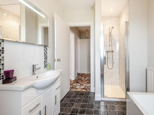 a white bathroom with a sink and a shower at Stackgarth in Gilcrux
