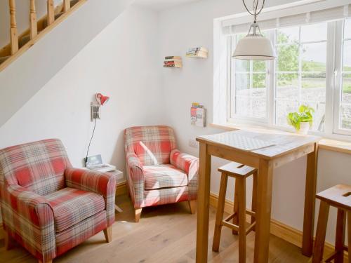 uma sala de estar com duas cadeiras e uma mesa em Riverbank Cottage em Kirkby Stephen