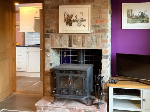 a fireplace in a kitchen with a stove at Newhouse Farm Barn in Neenton
