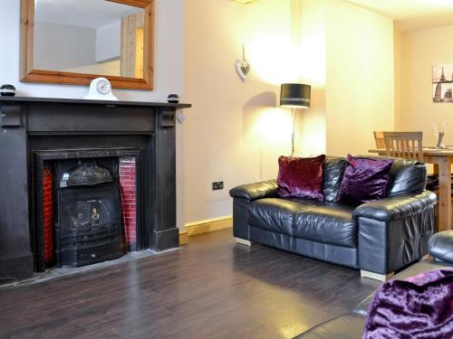 a living room with a black leather couch and a fireplace at Quarry Cottage in Bethesda