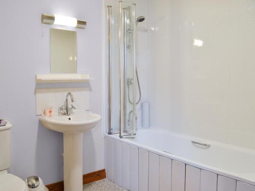 a white bathroom with a sink and a shower at Chalgrove in Aber-Brân