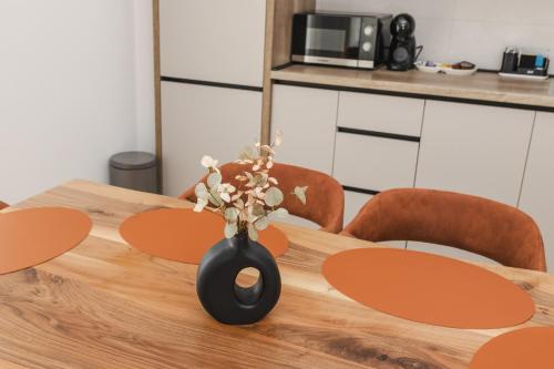 a wooden table with a vase with flowers in it at Autentica Apart in Cetinje