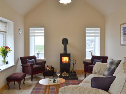a living room with a couch and a wood stove at Kilbride Beach Cottage in Pollachar