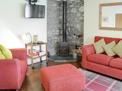 ein Wohnzimmer mit 2 roten Stühlen und einem Kamin in der Unterkunft Birch Cottage in Glenrossal