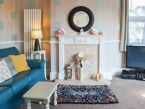 a living room with a blue couch and a fireplace at Deja Blue in Filey