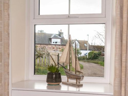una ventana con un bote de juguete en el alféizar de la ventana en Rosslyn Cottage, en Portmahomack