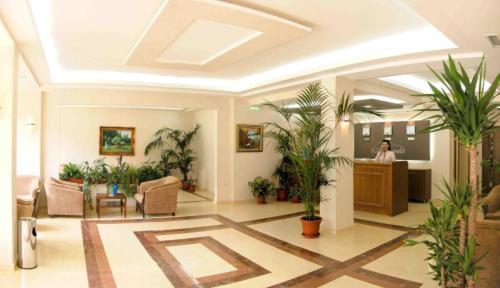 a lobby with potted plants and a woman in a room at Legends Hotel in Sofia