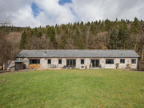 a stone house in a field with a yard at The Pendre Longbarn in Pentre-briwnant